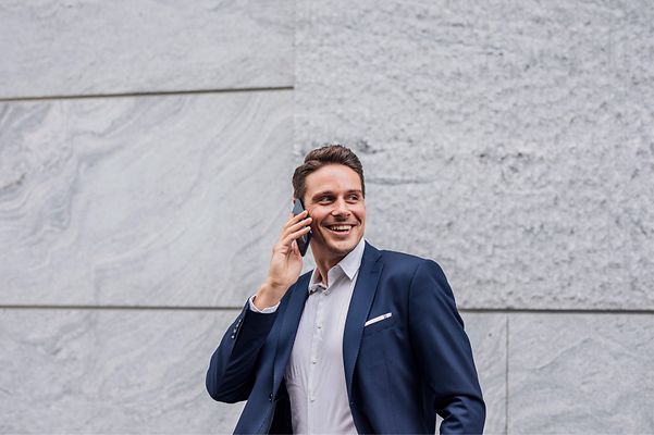 Mann mit Handy in der Hand telefoniert.